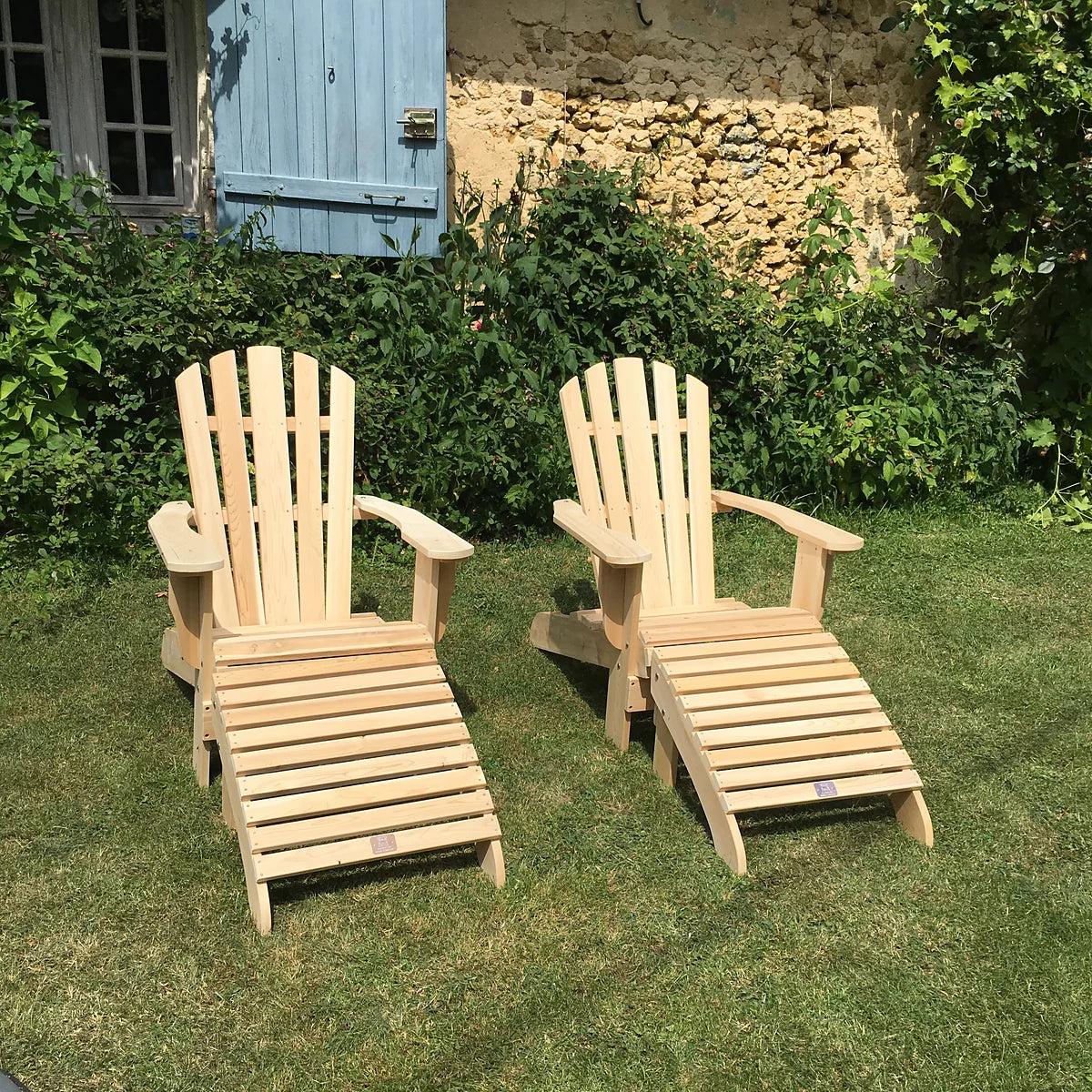 Deux fauteuils Adirondack avec repose-pieds en cèdre dans le jardin d'une maison en pierre